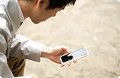 スマートフォンを手に持ち、画面を確認する作業員の横顔。